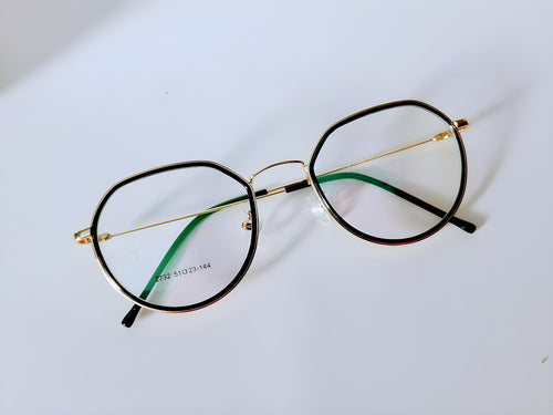 Black and gold oval eyeglass frames with green temple arms on white background