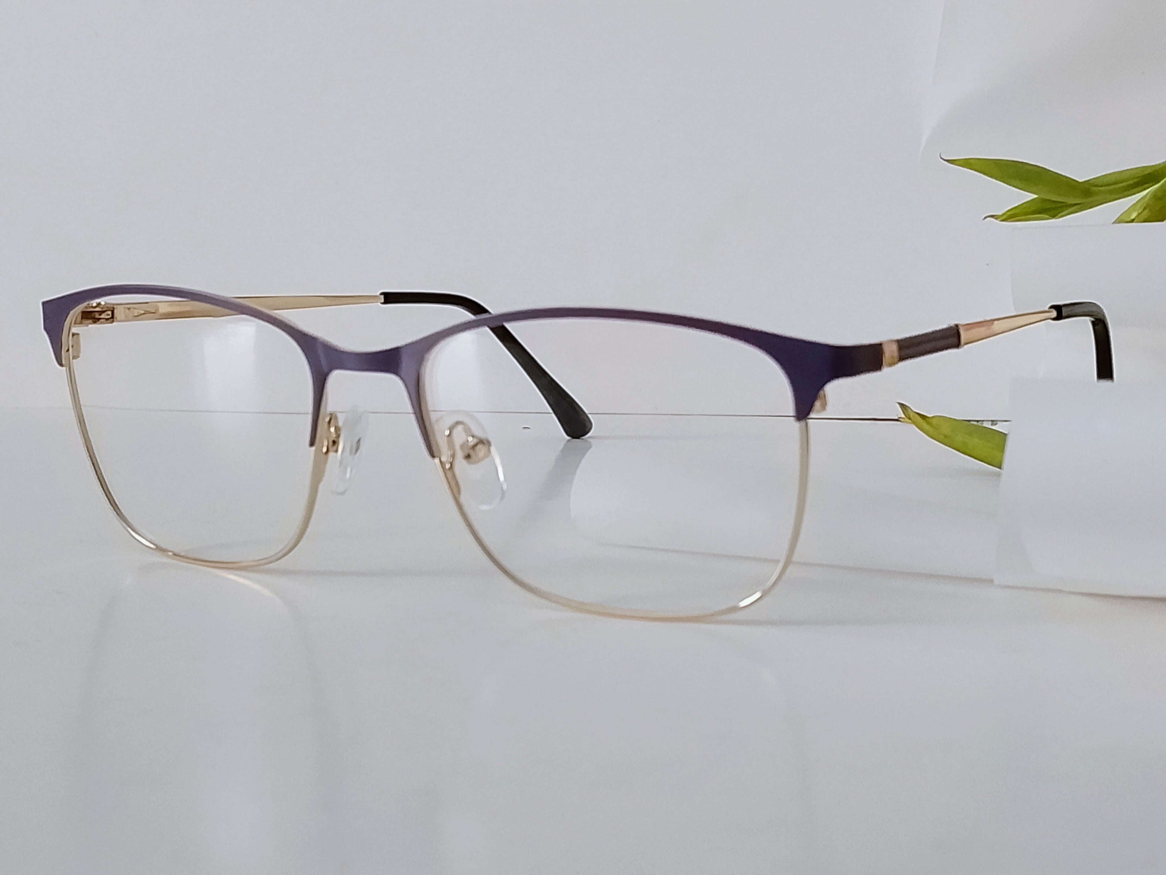 Purple and gold semi-rimless  stylish frame with clear lenses on white surface, modern optical frames