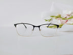 Black and gold semi-rimless eyeglasses with clear lenses on white surface, floral background