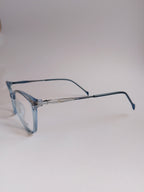 Light blue acetate eyeglass frames with a silver metal double bridge and thin dark blue temples, shown on a neutral light gray background.