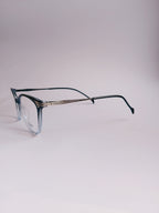 A pair of cat-eye eyeglasses with a translucent smoky blue acetate frame and dark green temples, featuring a thin silver metal double bridge, set against a plain light gray background.