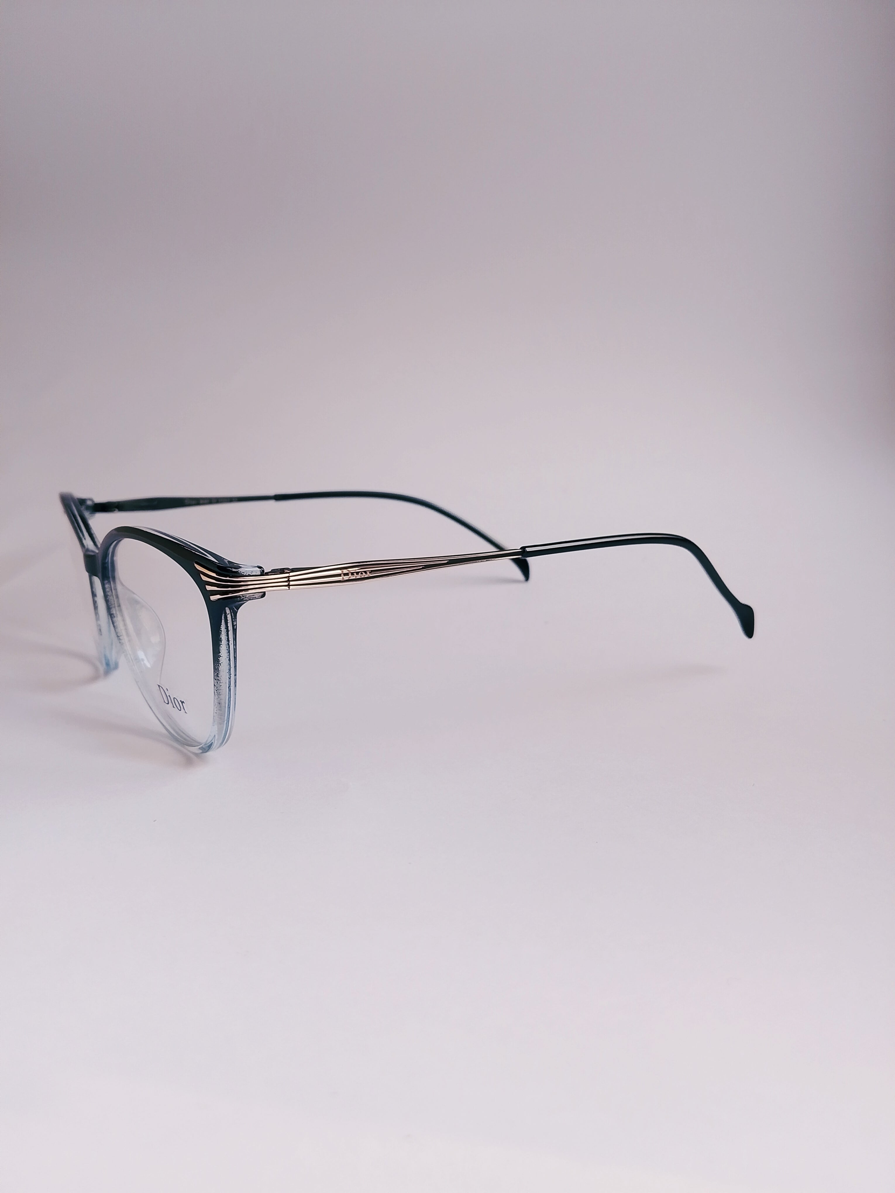 A pair of cat-eye eyeglasses with a translucent smoky blue acetate frame and dark green temples, featuring a thin silver metal double bridge, set against a plain light gray background.