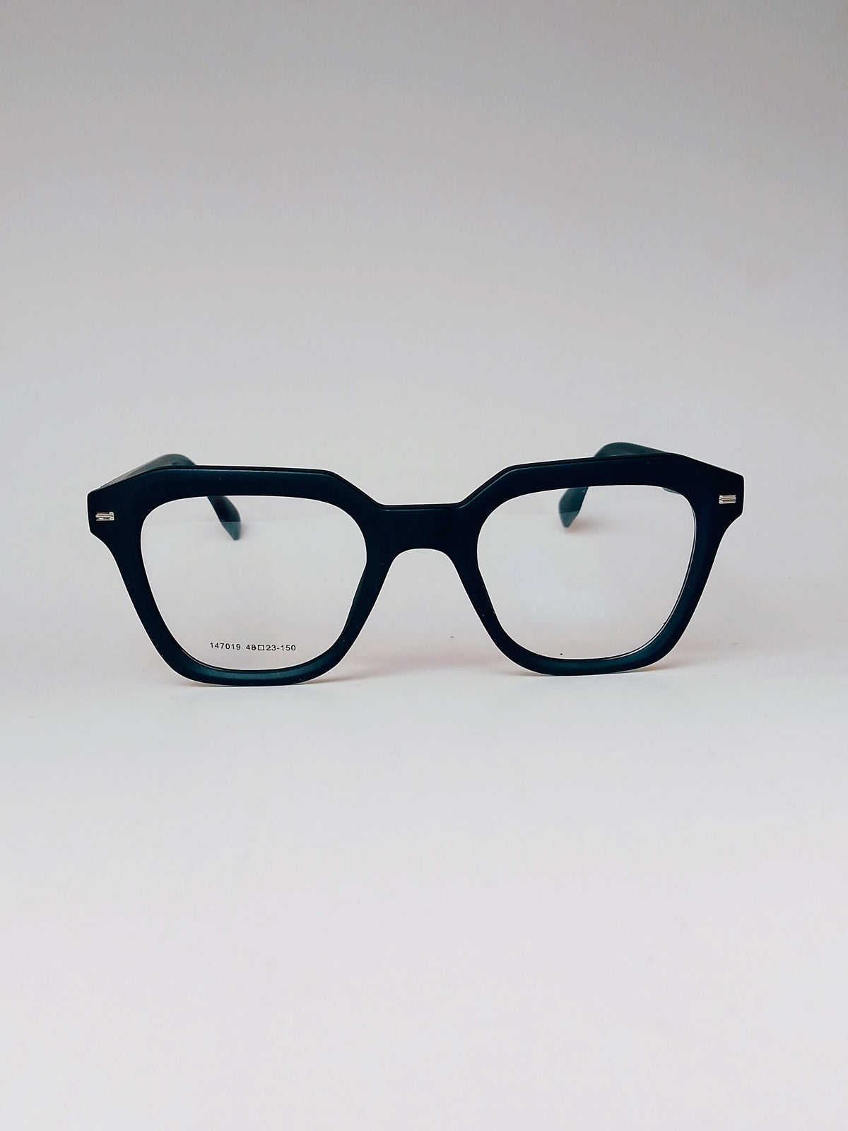 A pair of thick, dark navy blue acetate eyeglass frames with a unique geometric, slightly angular square shape. The clear lenses are visible, and the inner temple arms are a contrasting teal green.