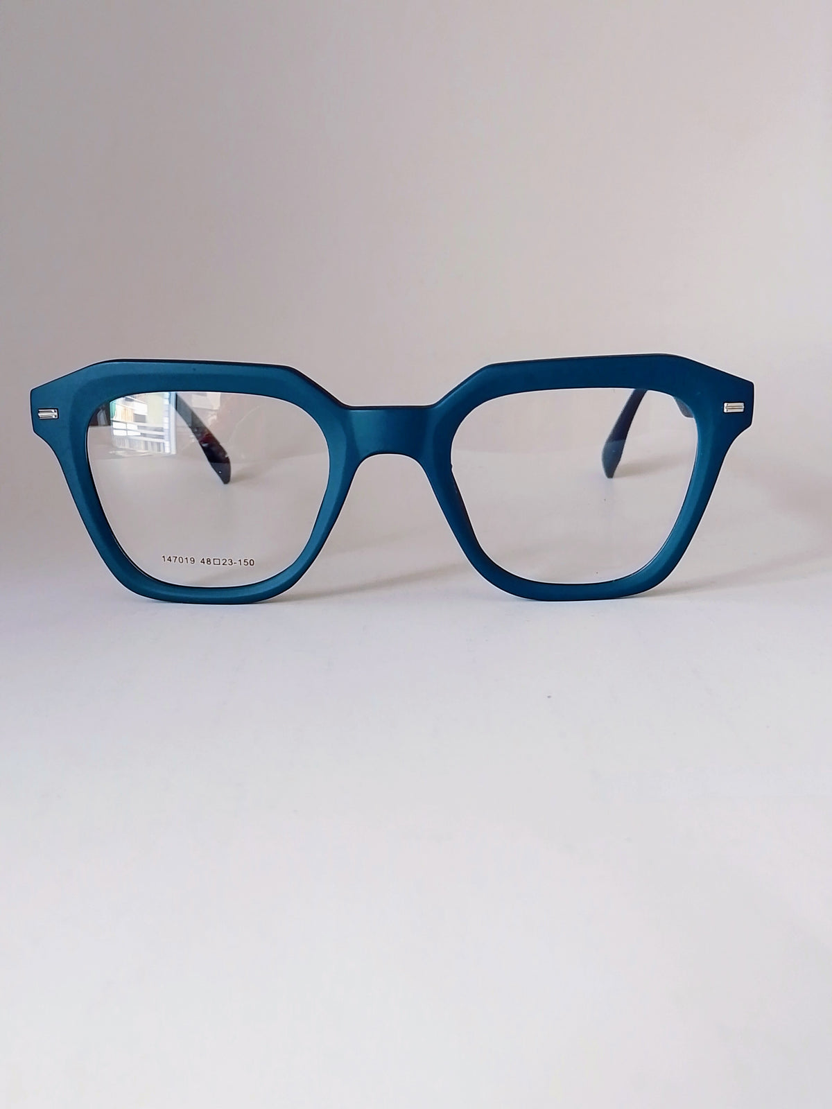 Matte blue square eyeglasses with clear lenses, displayed on a clean white surface against a light gray background.