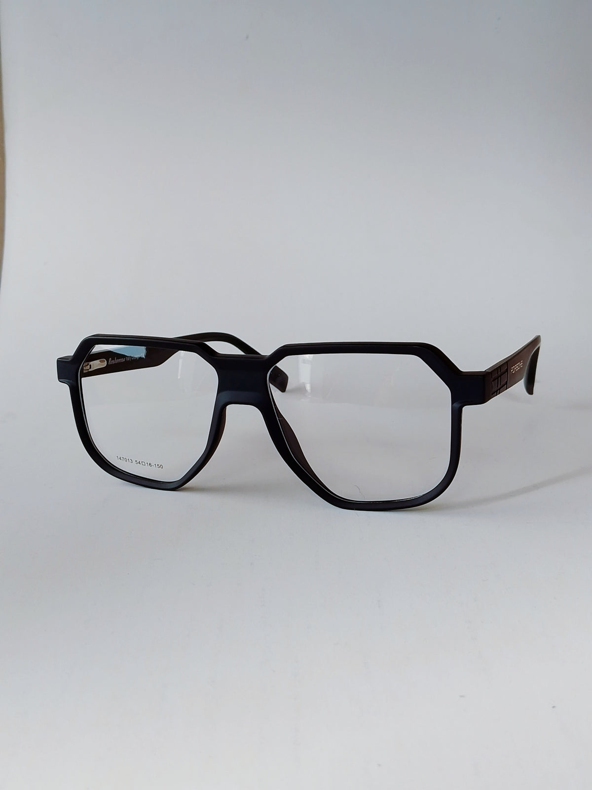 A pair of oversized square eyeglasses with a matte black frame and dark brown patterned temples, shown on a plain light gray background.