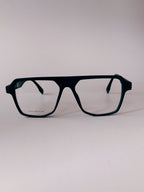 A pair of oversized square eyeglasses with a matte black frame and clear lenses, photographed against a neutral light gray background.
