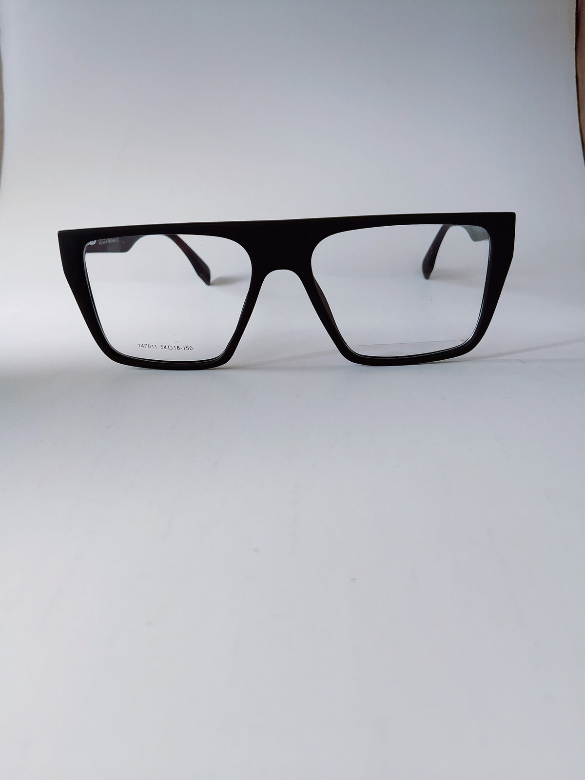 Black oversized square eyeglasses with clear lenses, displayed on a light gray background.
