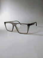 A pair of square-frame eyeglasses with a translucent taupe-gray acetate frame and clear lenses, resting on a light gray surface against a neutral background.