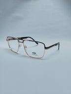 A pair of semi-rimless eyeglasses with a metallic rose gold frame and dark temples, displayed on a light gray background. 