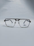 A pair of aviator-style eyeglasses with a thin black metal frame and clear lenses, resting on a light gray surface against a matching gray background. The brand name 'STEPPER' is visible on the lower right lens.