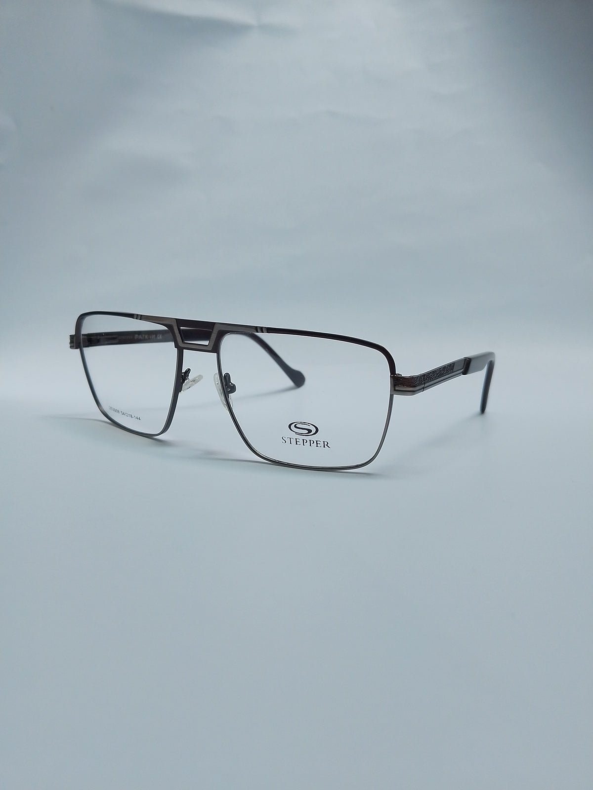 A pair of rectangular eyeglasses with a dark brown metal frame and clear lenses, resting on a light gray background. The brand name 'STEFFER' is printed on the lower part of the right lens.