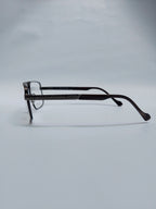 A pair of dark brown acetate eyeglasses with a square frame and thin temples, displayed on a light gray background.