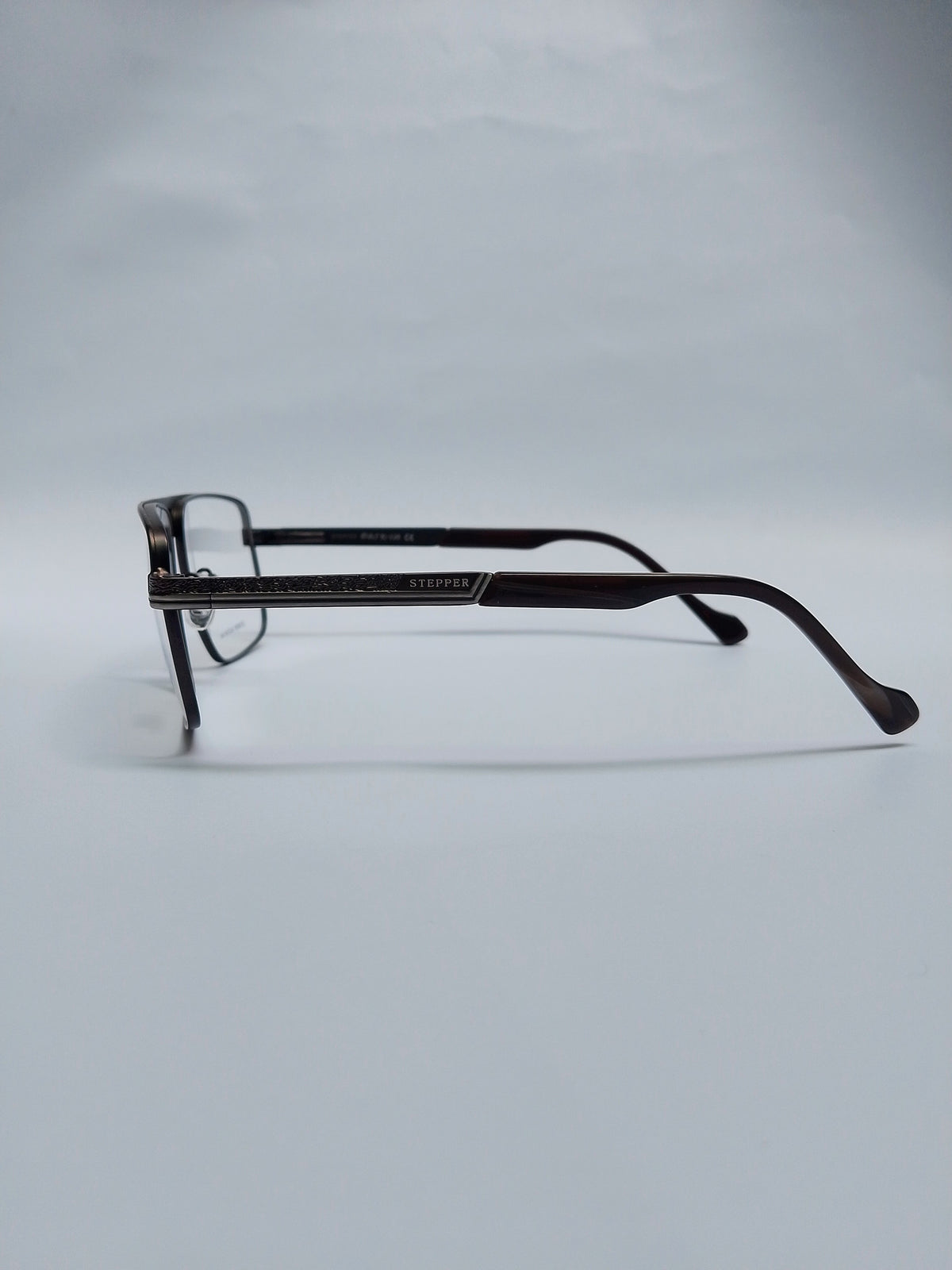 A pair of dark brown acetate eyeglasses with a square frame and thin temples, displayed on a light gray background.
