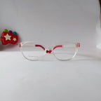 Clear acetate eyeglass frames with red inner temples and nose bridge, shown on a white background with a small red toy prop on the left.