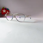 A pair of round metal eyeglasses with thin silver frames and clear lenses, resting on a white surface against a light gray background.