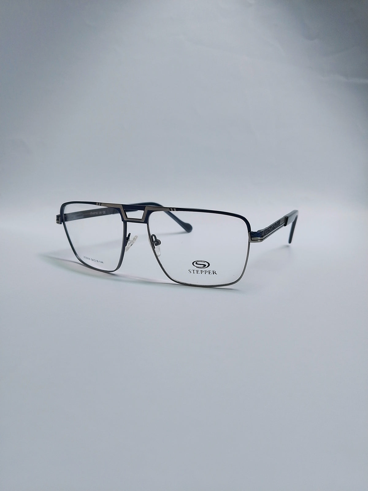 A pair of square metal eyeglasses with a dark gray and black frame, clear lenses, set against a light gray studio background.