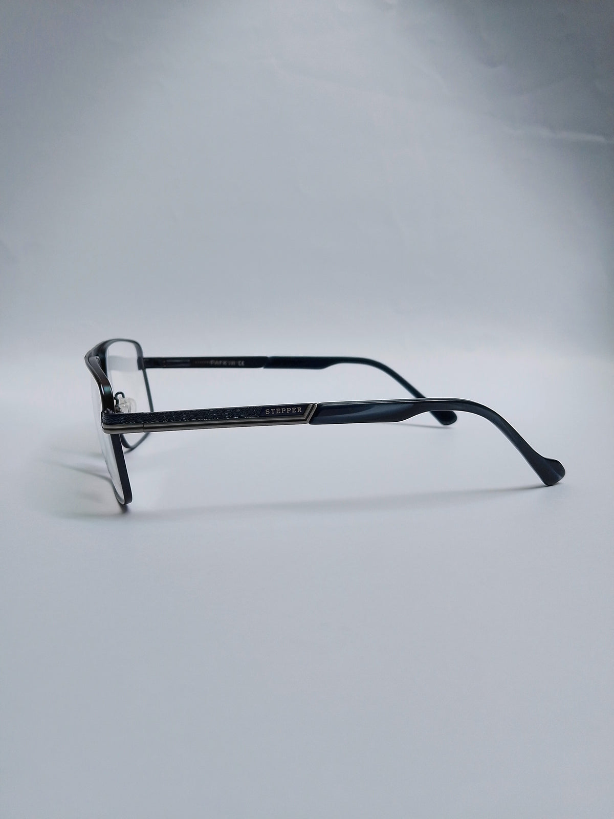 A pair of  eyeglasses with a black metal frame and dark  blur acetate temples, on gray studio light