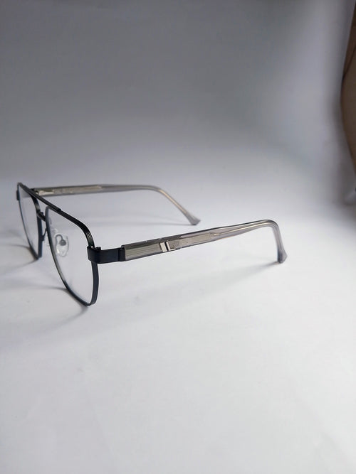 A pair of square aviator-style eyeglasses with a black front frame and silver metal temples, resting on a white surface against a gray background.