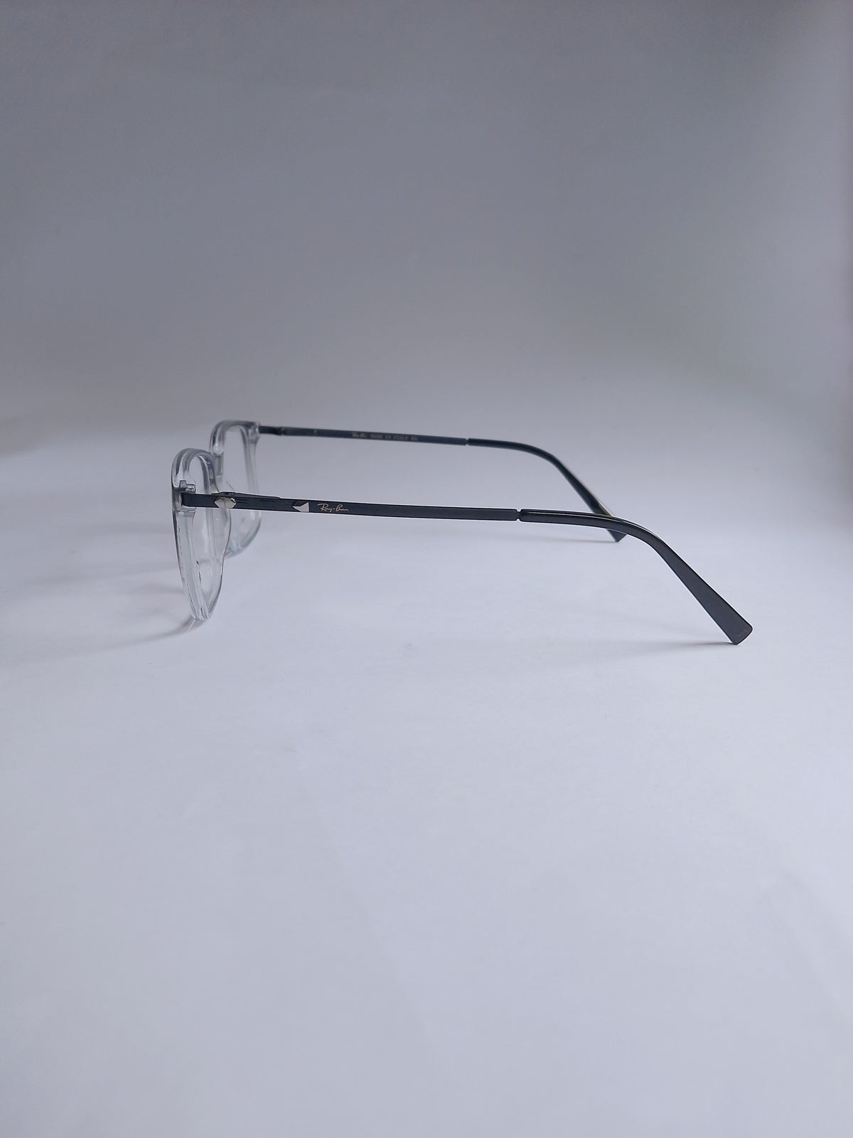 A temple arm view, with a slim black metal temples, photographed on a seamless light gray studio background.