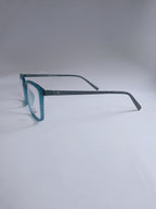 A pair of vintage-style square eyeglasses with a translucent teal-blue frame and dark gray temples, displayed on a light gray background.