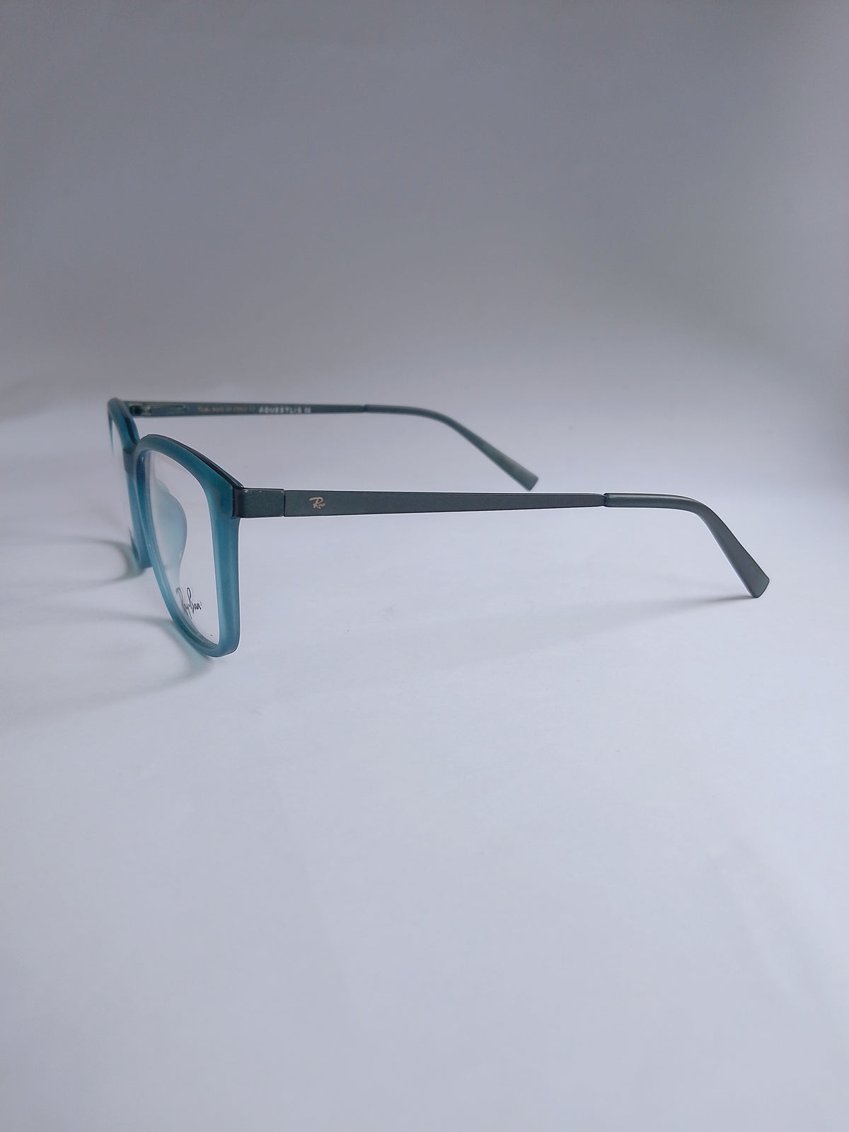 A pair of vintage-style square eyeglasses with a translucent teal-blue frame and dark gray temples, displayed on a light gray background.