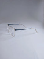 A pair of square-frame eyeglasses with clear acetate frames and slim blue temples, photographed on a light gray studio background.