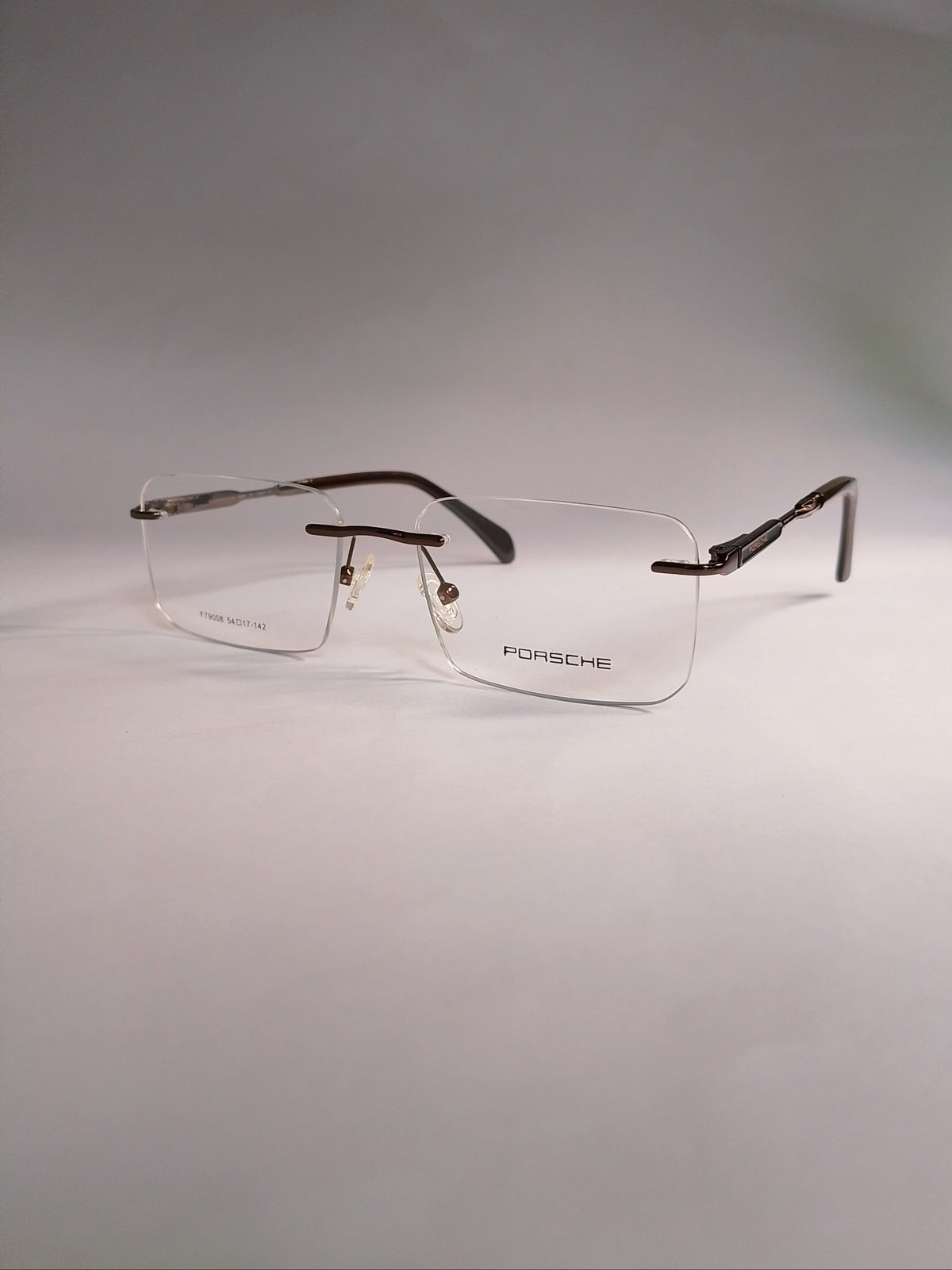  rimless eyeglasses with a clear full-rim front and dark brown tortoiseshell temples, displayed on a light gray background.