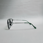 A pair of square-frame eyeglasses with a black and silver metal frame and dark green temple tips, photographed on a light gray fabric background.