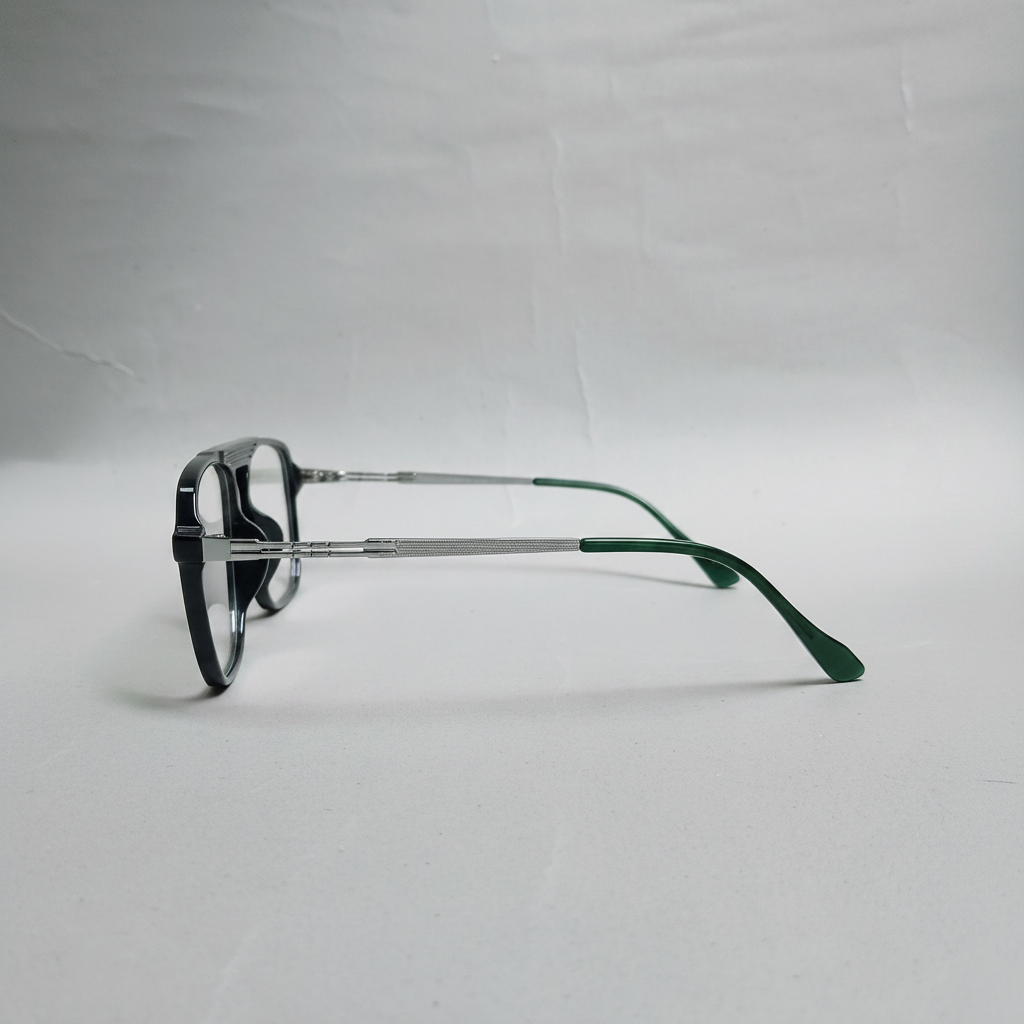 A pair of square-frame eyeglasses with a black and silver metal frame and dark green temple tips, photographed on a light gray fabric background.