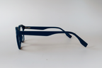 A pair of thick, dark navy blue acetate eyeglass frames with a square front and full rims, displayed in side profile on a clean white background.