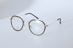 Gold and black round frame eyeglasses with clear lenses on white background