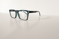 Teal rectangular eyeglasses with clear lenses on white surface, modern optical frames for men or women