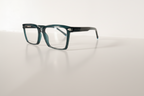 Teal rectangular eyeglasses with clear lenses on white surface, modern optical frames for men or women